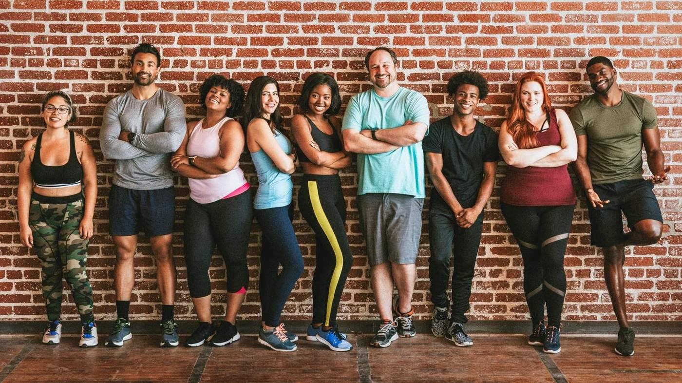 Collaborateurs en tenue de sport réunis contre un mur de brique